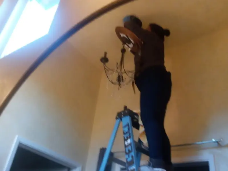 Electrician installing a chandelier in a Four Square Mile residence
